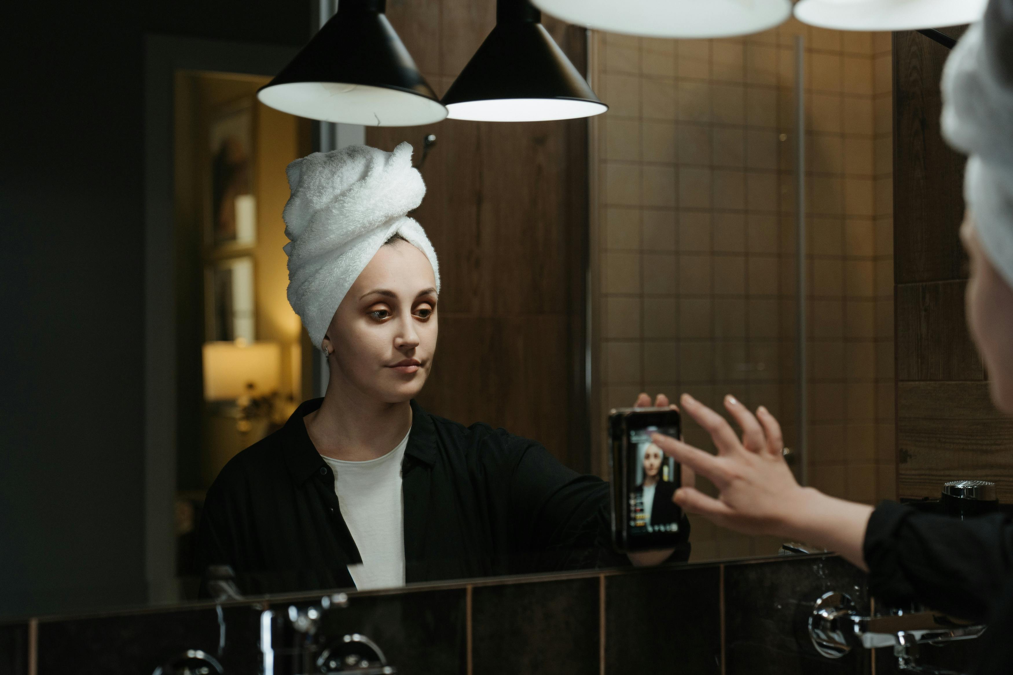 Жінка наносить макіяж, дивлячись у дзеркало